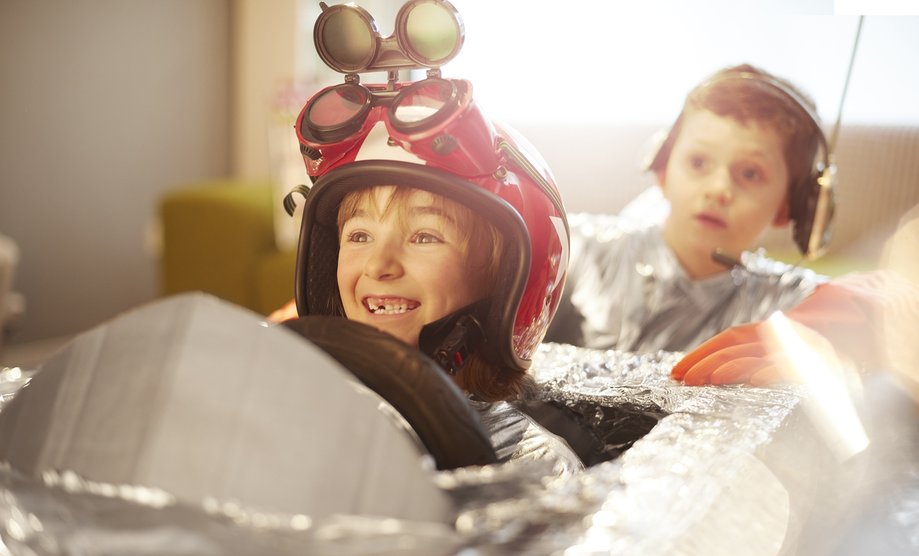 a young girl and boy have made a rocket ship and jetpack and are role playing a lift off