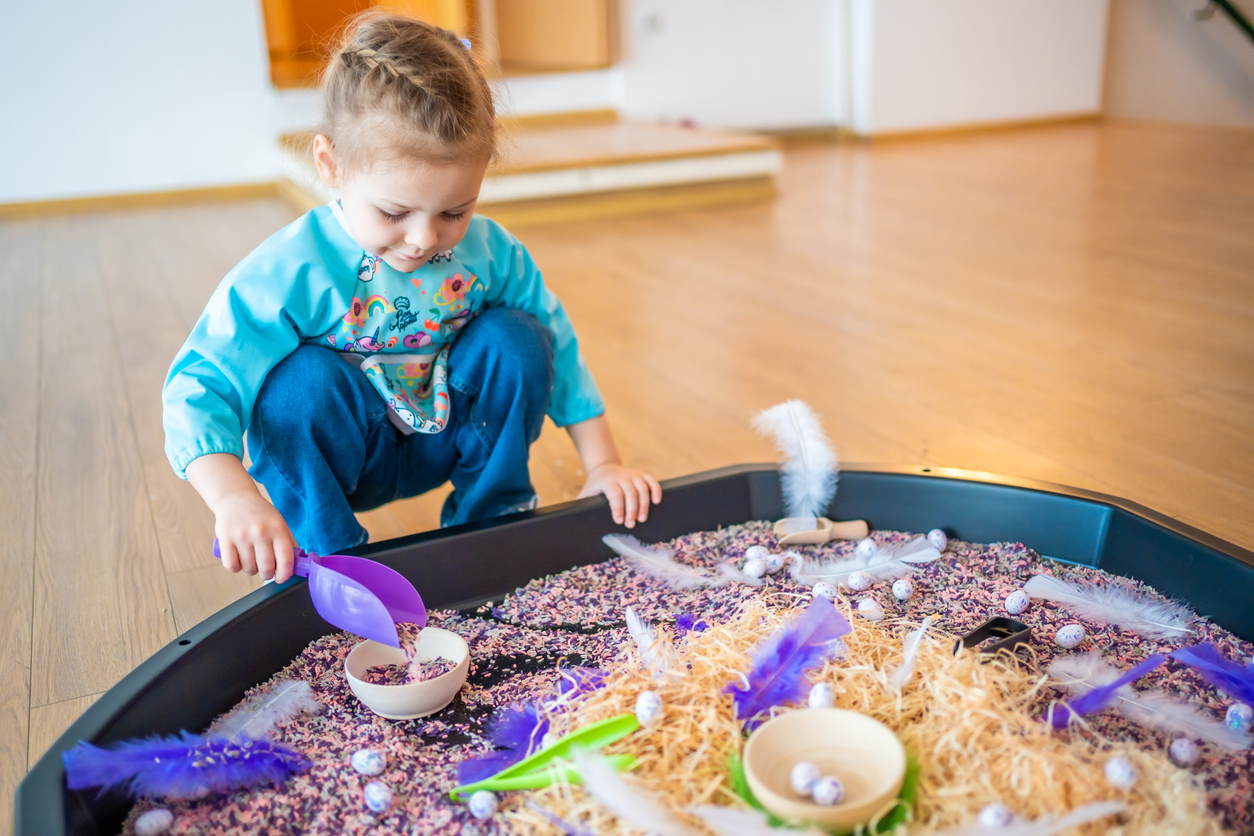 Little girl playing with sensory colorful rice. Sensory development and experiences, themed activities with children, fine motor skills development